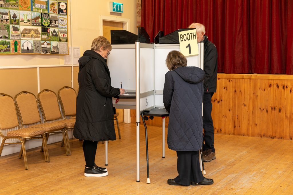 People completing their ballot paper at a polling station.