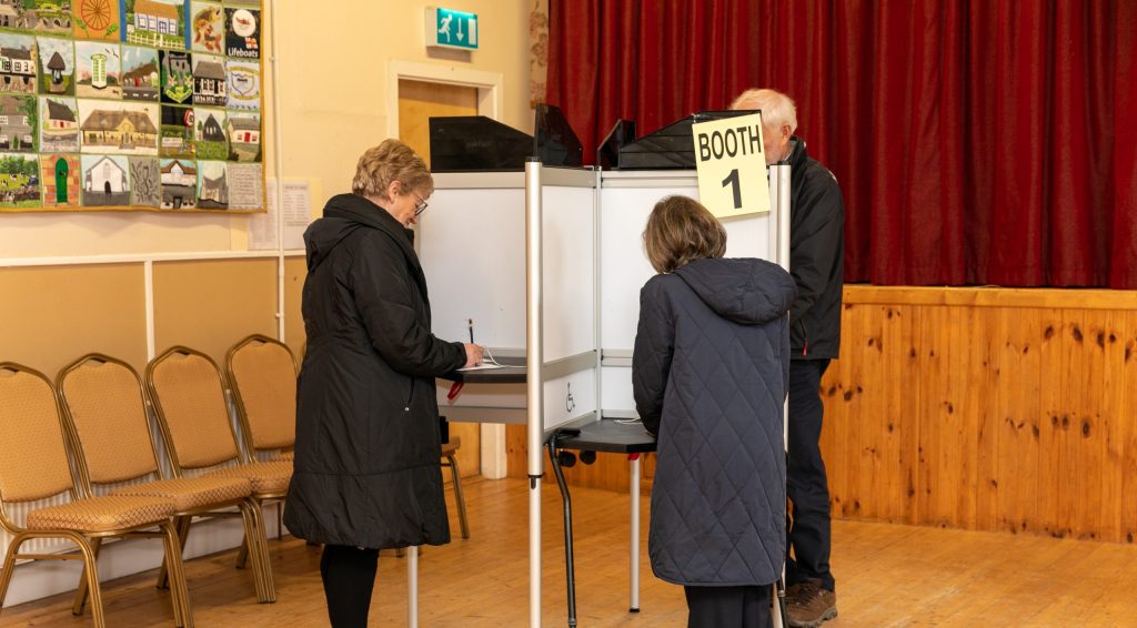 People completing their ballot paper at a polling station.
